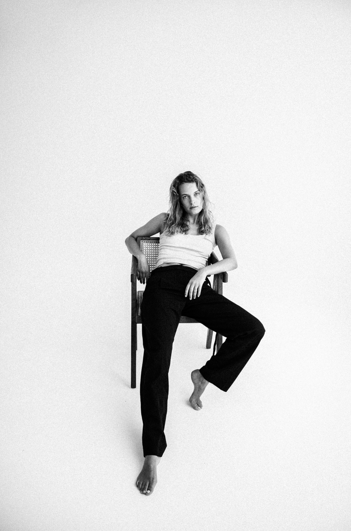 girl in black and white outfit sitting on a chair in a white studio for a black and white photograph