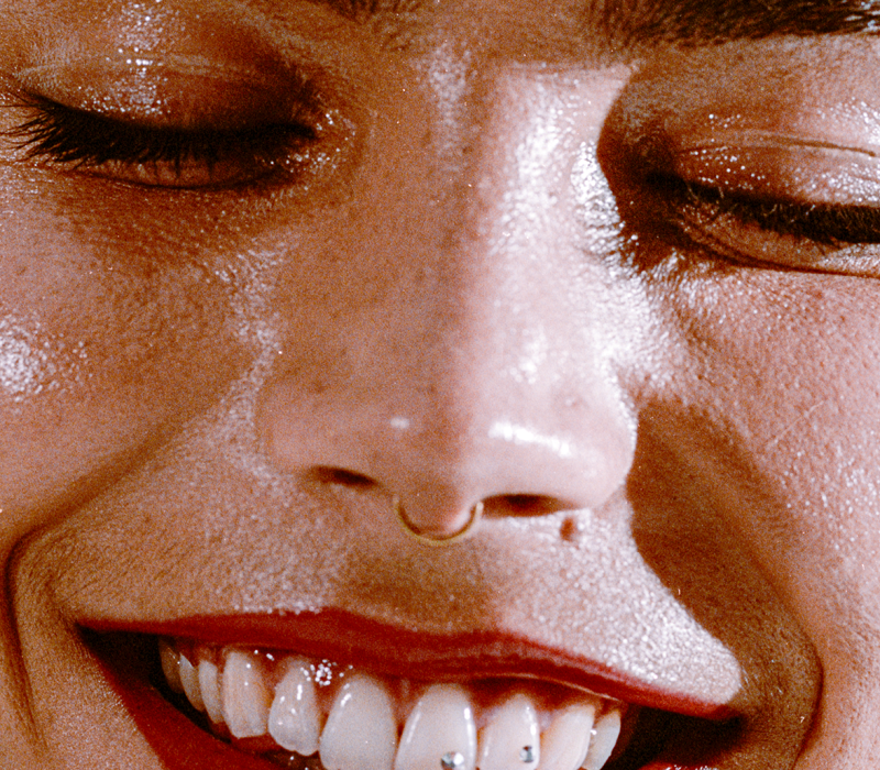 close up portrait of a girl wearing red lipstick, smiling, with eyes closed