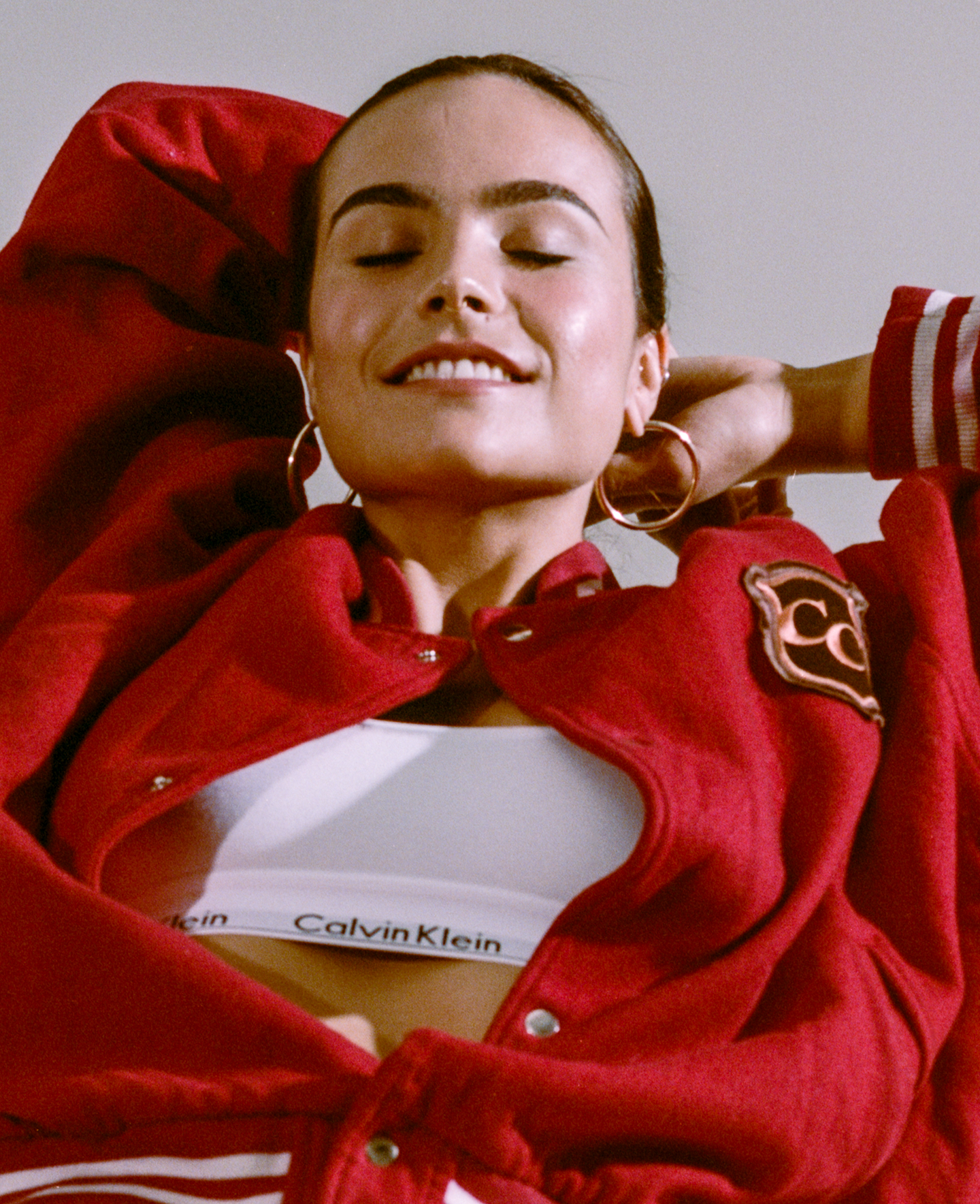 portrait of a girl in red jacket with white calvin klein bra and big hoop earrings
